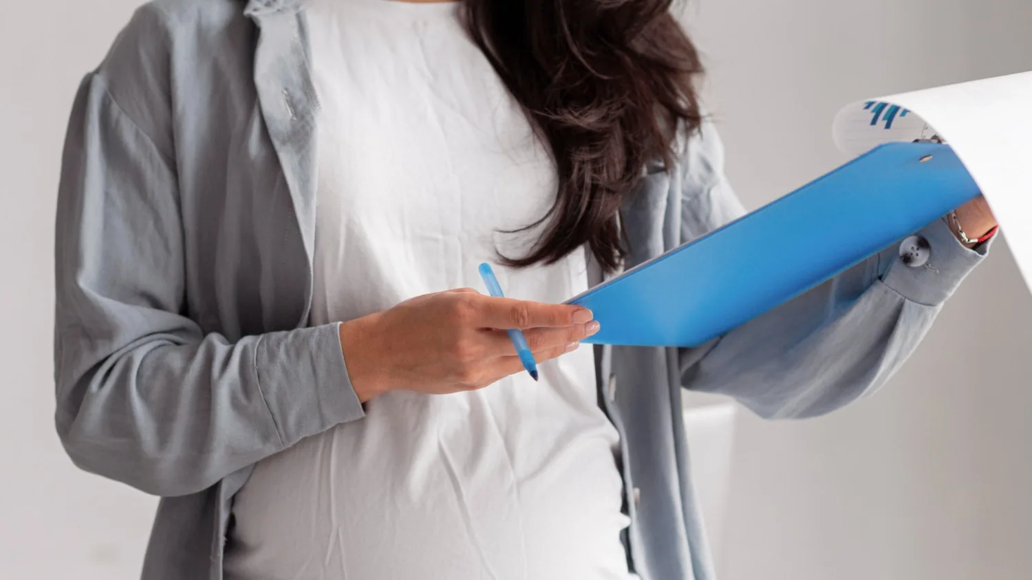 pregnant woman holding clipboard with paper